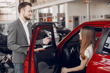 Lady in a car salon. Woman buying the car. Elegant woman in a dress. Assistent with a client