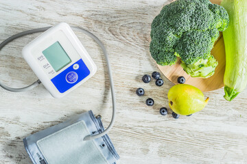 Blood pressure monitor on a table next to table of green fruits and vegetables