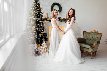 Beautiful bride in luxury wedding dress and pretty bridesmaid in dresse in decorated christmas...