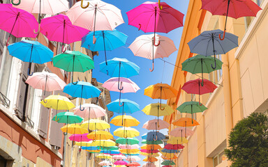 Fototapeta na wymiar Rue piétonne à Carcassonne colorée de parapluie multicolore suspendue en l'air
