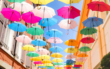 Fototapeta na wymiar Rue piétonne colorée de parapluie multicolore suspendue dans les airs à Carcassonne