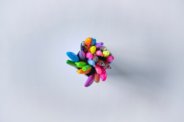 Top view of colorful pens in a white cup