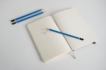 Notebook with a sketch and pencils on a white desk