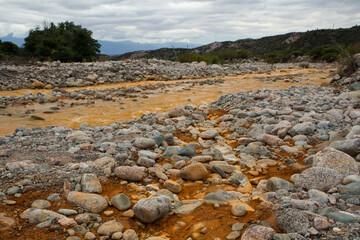 Unique yellow river called River of Gold due to the presence of iron in the water, flowing across the rocky valley and mountains in La Rioja, Argentina.