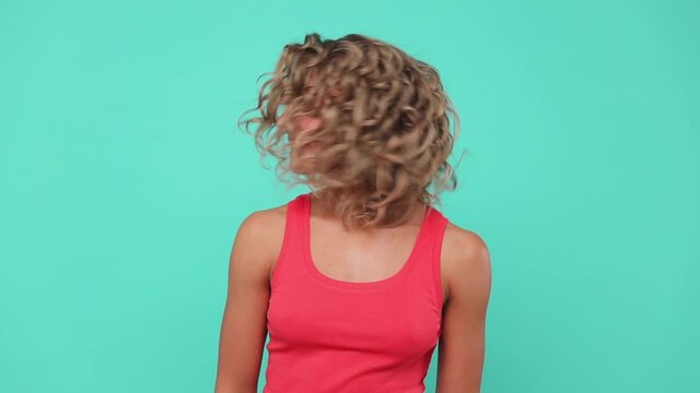 Smiling laughing funny blonde young woman 20s years old in pink tank top posing isolated on blue turquoise colour background studio. People lifestyle concept. Keeping eyes closed shaking head dancing