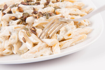 Pasta with blue cheese and cream sauce, sprinkled with roasted pumpkin seeds eaten with a fork