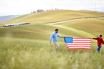 A couple holding unfurled American flag at the meadow. Election, campaign, freedom concept