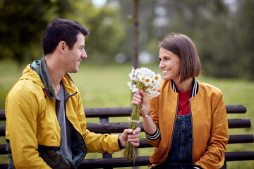 Man giving bouquet of flowers to a woman; Happy couple concept