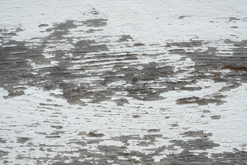 peeling white paint on a weathered gray plank of wood