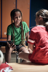 Kids listening to the music on smartphone before training. Children team sport