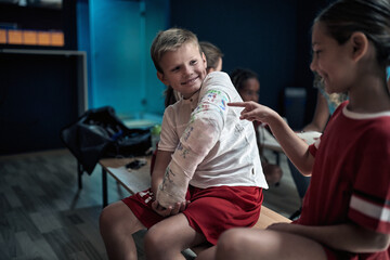 Little teammates observing autographs on broken arm in gypsum. Children team sport