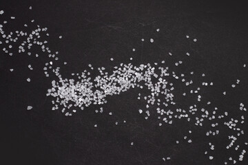 Spilled white sea salt on a black background. clear crystalline pebbles on a black background