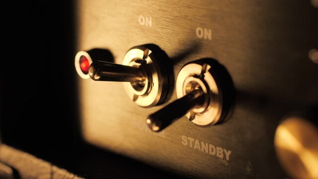 Turning on a guitar amplifier power switch slow motion macro closeup
