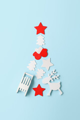 Alternative Christmas tree. Top view of Christmas tree made from different wooden decoration on pastel blue background. Vertical orientation, flat lay.