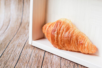 Fresh croissants on a wooden table and on the bamboo basket.