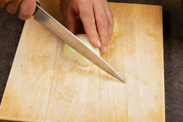 The hands cutting onions on a chopping board