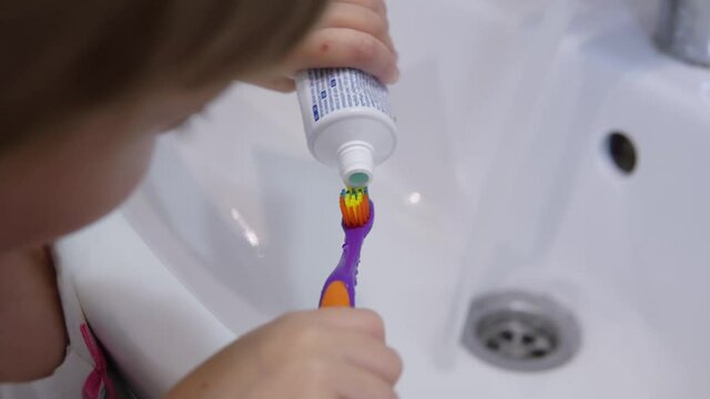 Girl squeezes toothpaste onto a toothbrush