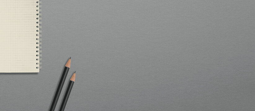 Black pencils and a notebook on the table. View from above. Gray background