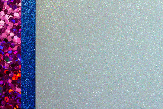 Full frame sparkling light silver blue glitter texture background with dark red and blue glitter border. With bokeh and copy space.