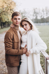 Beautiful young couple in autumn walks with dogs, pomeranian, in the park