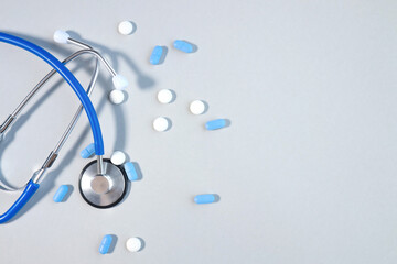 Pills or pills lying next to stethoscope on gray background with conceptual copy space medicine, healthcare and medication treatment
