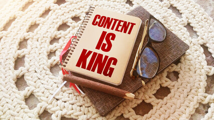 Cover of notebook with words Content Is King, glasses and pen. Storytelling copywriting business and education concept