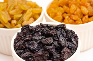 Multicolored raisins in white plates on a white background