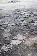 Destroyed road in poor condition requiring repair. Holes in the asphalt are filled with water and puddles. Stock photo background