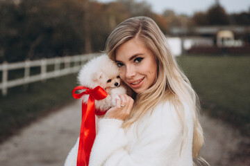 Beautiful young couple in autumn walks with dogs, pomeranian, in the park