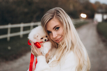 Beautiful young couple in autumn walks with dogs, pomeranian, in the park