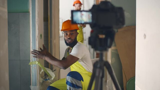 Portrait of african renovation worker filming video about wall construction on camera