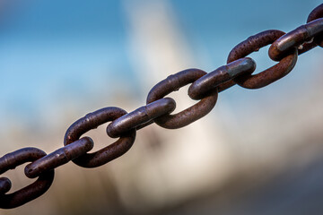 Une chaîne traverse l'image du bas à gauche vers le haut à droite. À l'arrière-plan, un immeuble très flou.