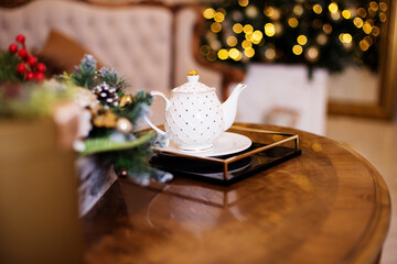 White teapot for making tea on the table, against the background of a Christmas tree. Tea ceremony. New year's concept 2021
