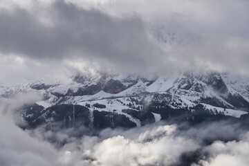 Forested mountain slope in low lying cloud with the evergreen conifers shrouded in mist in a scenic landscape view and snow in the dolomites