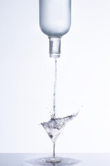 Botella desocupándose en una copa mientras se riega, sirviendo licor en copa, splash