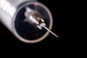 syringe or injection on isolated black background, with spot focus on the tip of the needle