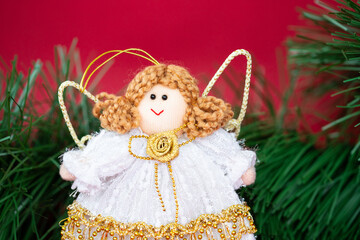 A handmade fabric angel with a background of green Christmas tree branches. A symbol of holiness and special time for people.