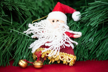 Textile Santa Claus lying in the vicinity of a Christmas tree branch. Handmade Christmas decoration.