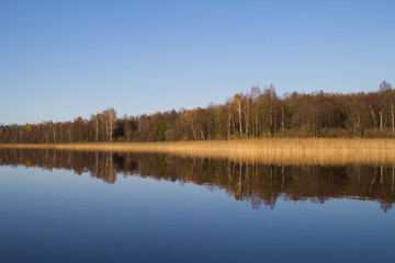 The autumn forest is reflected in the lake water.The concept of a private holiday. Horizontal orientation