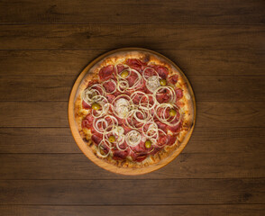 Pepperoni pizza, slices of onions, mozzarella cheese and green olives. On a wooden board. Top gastronomic photography, with ample spaces for texts and graphic arts. Food in the center.