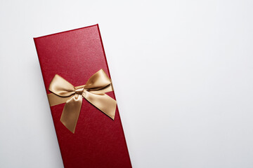 Close-up of Christmas gift box of red color with golden bow, isolated on white background with copy space.