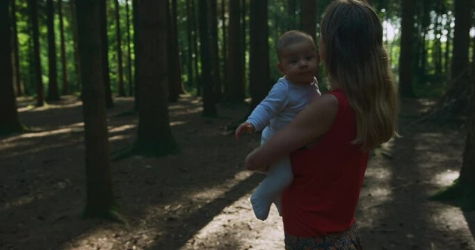 A young mother is walking in the forest with her baby in autumn