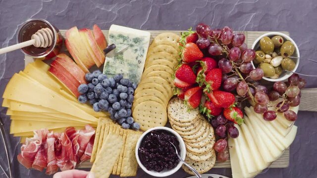 Flat lay. Arranging gourmet cheese, crakers, and fruits on a board for a large cheese board.