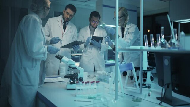 Team of Medical Research Scientists Have Meeting and Conduct Experiments with Help of DNA Samples in Test Tubes and Microscope Slides. Applied Science Laboratory with Diverse Multicultural Colleagues.