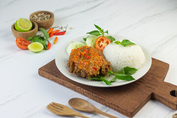 Ayam geprek, Indonesian popular streed food, made from crispy chicken smashed with sambal or chili sauce, eat with rice and cucumber, lettuce, tomato and kemangi. Isolated background, copy space.