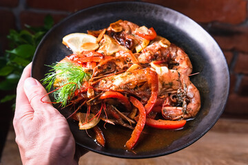 Delicious fried langoustines in sauce on a black plate, prepared in an Asian style. Fast and ready meal concept