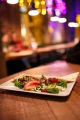 Serve vegetable salad in a white plate. Cozy wooden pub