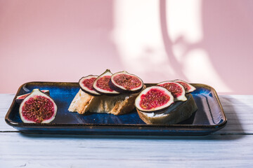Bruschetta of baguette, cheese and figs are on a plate on the table. The concept of minimalism in...