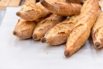 Freshly baked French baguettes lie on a light-colored surface. Rustic handicraft bread, handmade