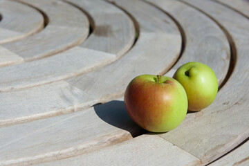 Two freshly grown vibrant apples lie on concentric circles of a table